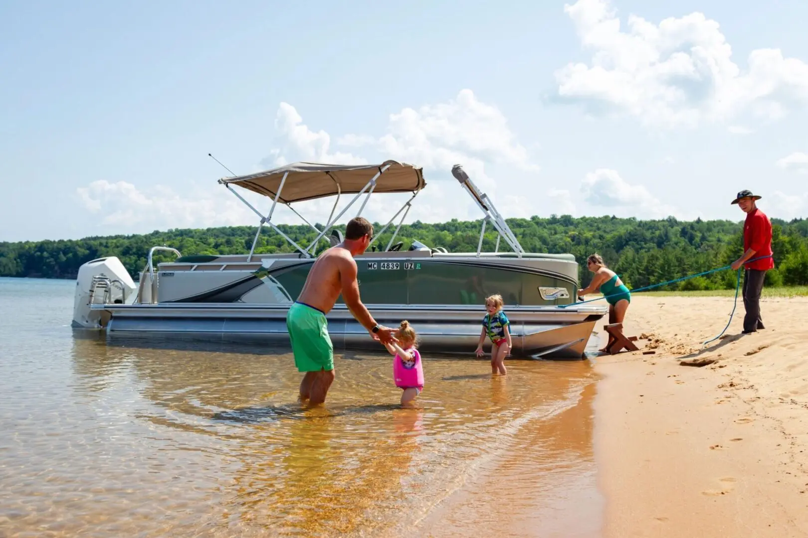 A family is standing in the water near their boat.