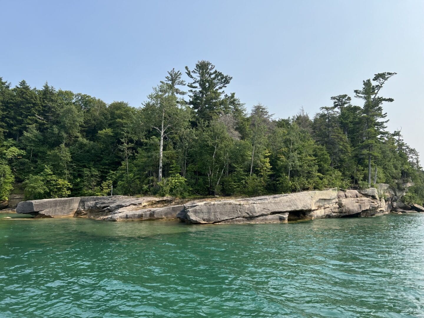 A body of water with trees and rocks in the background.