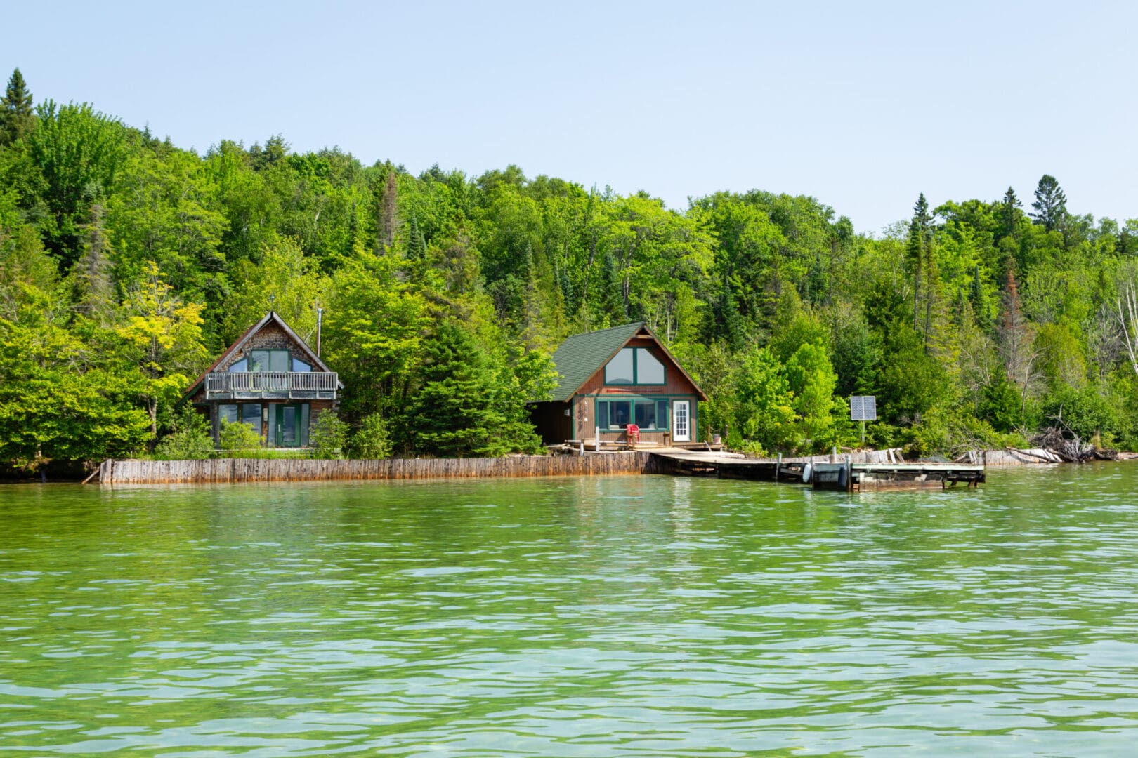 A lake with three houses on it and trees in the background.