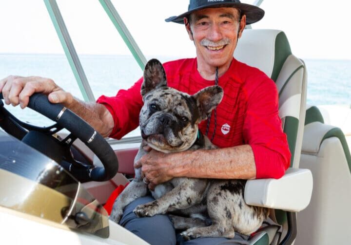 A man and his dog are in the boat.