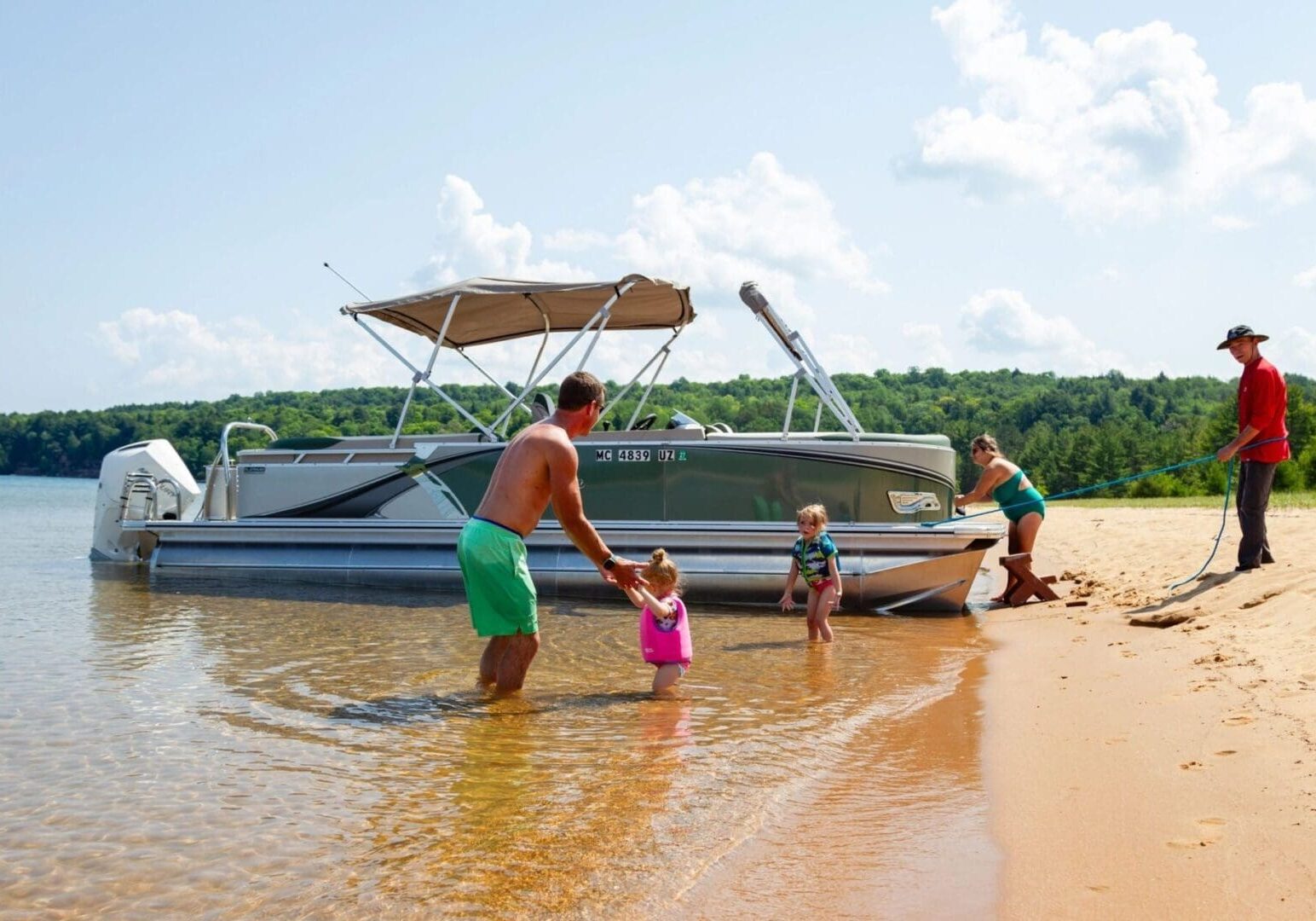 A family is standing in the water near their boat.